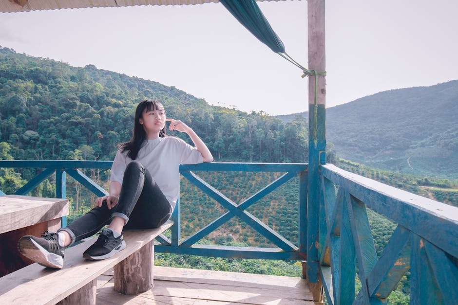 Person viewed from behind, meditating on a wooden deck in nature