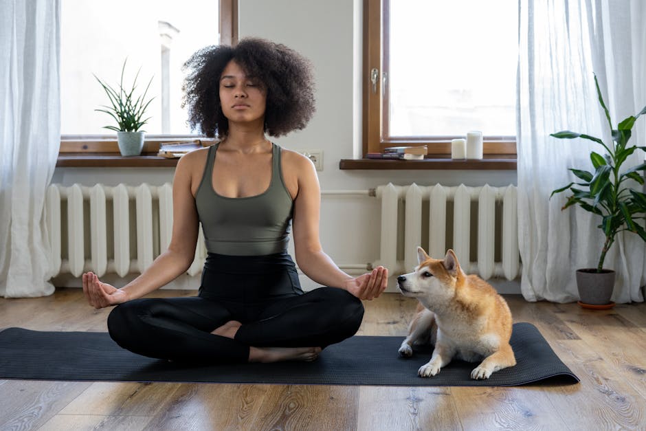 Woman meditating peacefully on a yoga mat by a large sunlit window